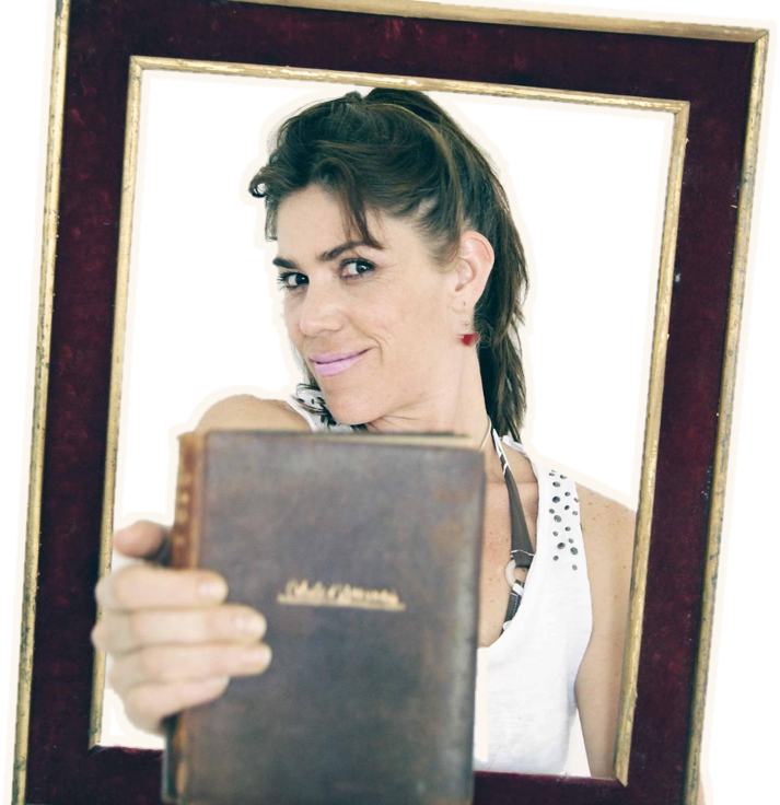 Marcela Magdaleno sonríe dentro de un marco y ofrece un libro antiguo